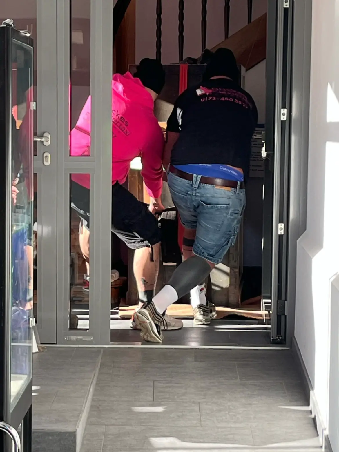 Mitarbeiter bringen ein verpacktes Instrument durch eine Haustür in ein Gebäude