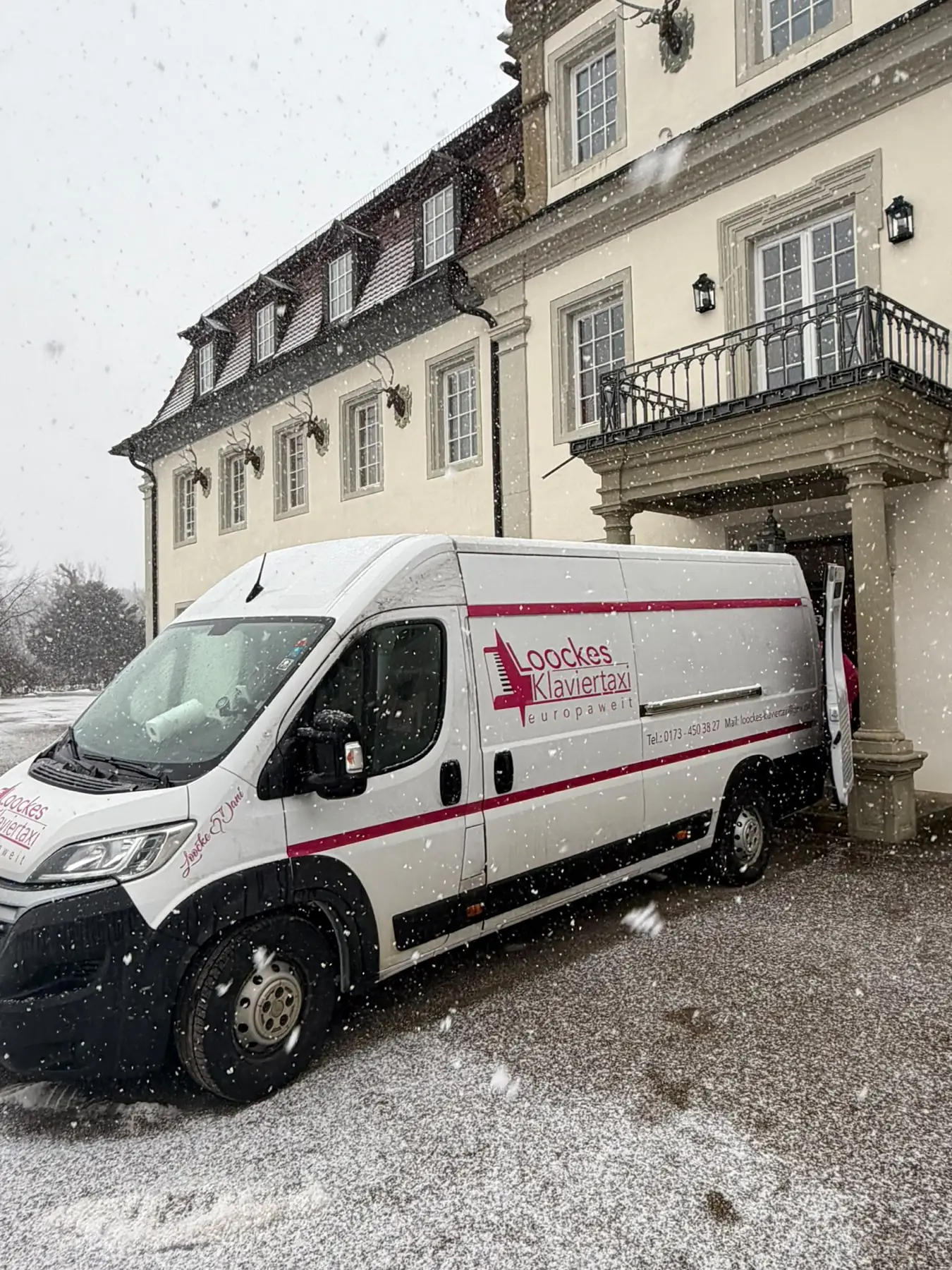 Transporter von Loocke's Klaviertaxi bei Schneefall vor einem historischen Gebäude